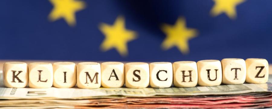 Klimaschutz auf Würfeln geschrieben, EU Flagge im Hintergrund
