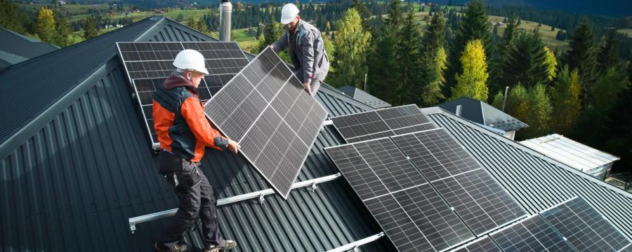 Männer bauen eine Photovoltaik-Anlage auf dem Dach