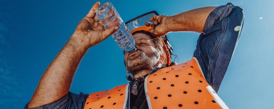 Bauarbeiter trinkt in der Hitze ein Glas Wasser