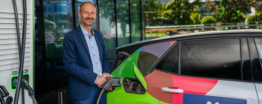 Mann steht an einer E-Tankstelle und will sein Auto laden.